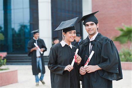 student graduating - Portrait of graduate students holding diplomas and smiling in university campus Stock Photo - Premium Royalty-Free, Code: 630-06724600