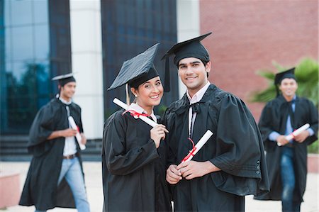Portrait of graduate students holding diplomas and smiling in university campus Stock Photo - Premium Royalty-Free, Code: 630-06724601