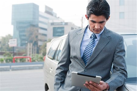 Businessman standing beside a car and using a digital tablet, Gurgaon, Haryana, India Foto de stock - Sin royalties Premium, Código: 630-06724616