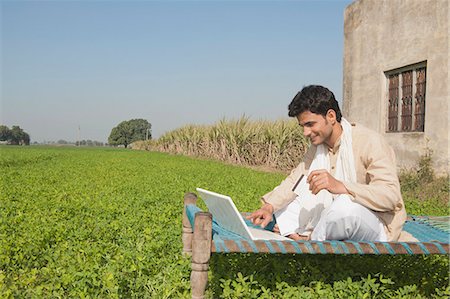 farmer asia - Farmer using a laptop and holding a credit card in the field, Sonipat, Haryana, India Stock Photo - Premium Royalty-Free, Code: 630-06724659