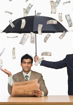 Money falling on businessman sitting under an umbrella Stock Photo - Premium Royalty-Free, Code: 630-06721854
