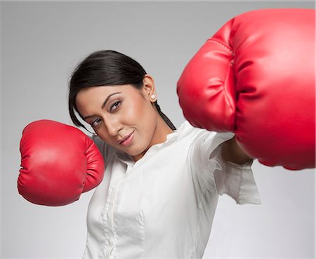 Businesswoman punching with boxing gloves Stock Photo - Premium Royalty-Free, Code: 630-06722012