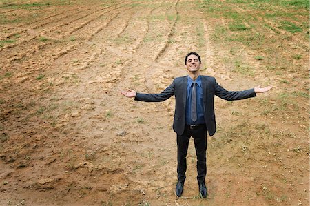 Businessman standing with arm outstretched in a field Stock Photo - Premium Royalty-Free, Code: 630-06722925