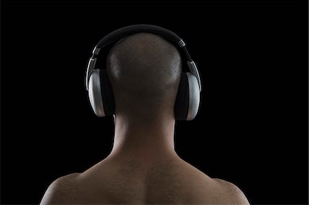 shaved head - Rear view of a man listening to headphones Stock Photo - Premium Royalty-Free, Code: 630-06723146