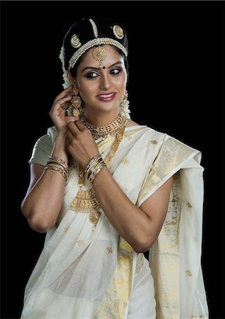 Indian woman in traditional clothing adjusting her earrings Stock Photo - Premium Royalty-Free, Code: 630-06723384