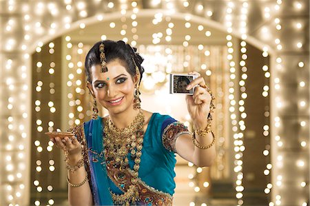 festival photo indian - Woman holding an oil lamp and taking a picture of herself with a digital camera Stock Photo - Premium Royalty-Free, Code: 630-06723561