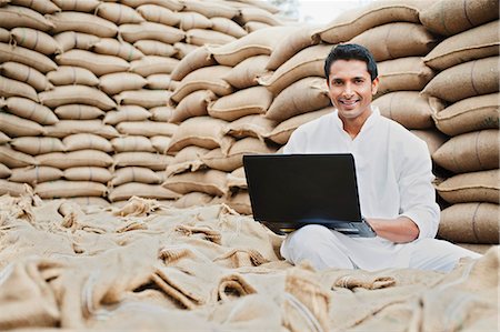 Man using a laptop in a grains market, Anaj Mandi, Sohna, Gurgaon, Haryana, India Foto de stock - Sin royalties Premium, Código: 630-07071187