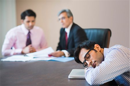 Businessman sleeping in a conference with two businessmen in the background Stock Photo - Premium Royalty-Free, Code: 630-07071463