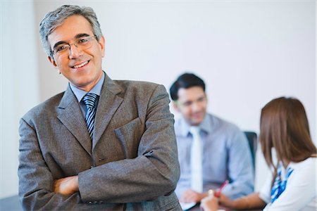 simsearch:630-07071502,k - Portrait of a businessman smiling with his colleagues discussing in the background Stock Photo - Premium Royalty-Free, Code: 630-07071474