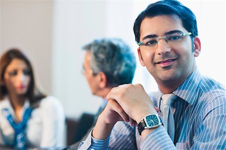 simsearch:630-07071502,k - Portrait of a businessman smiling with his colleagues discussing in the background Stock Photo - Premium Royalty-Free, Code: 630-07071477