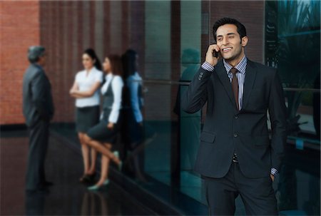 simsearch:630-07071502,k - Businessman talking on a mobile phone with their colleagues in the background Stock Photo - Premium Royalty-Free, Code: 630-07071589
