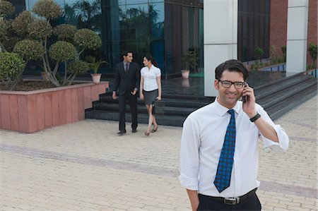 simsearch:630-06724175,k - Businessman talking on a mobile phone with their colleagues in the background Stock Photo - Premium Royalty-Free, Code: 630-07071595