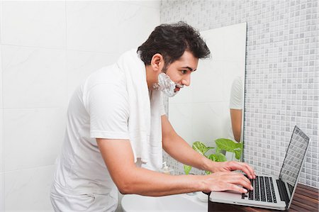 simsearch:700-02244629,k - Man using a laptop while shaving his face Photographie de stock - Premium Libres de Droits, Code: 630-07071609