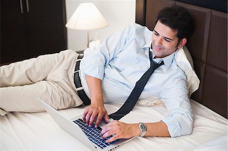 Businessman working on a laptop on the bed Stock Photo - Premium Royalty-Free, Code: 630-07071639