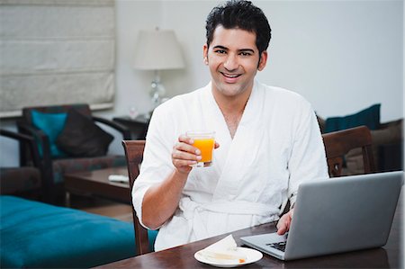 Businessman eating breakfast and working on a laptop Stock Photo - Premium Royalty-Free, Code: 630-07071697