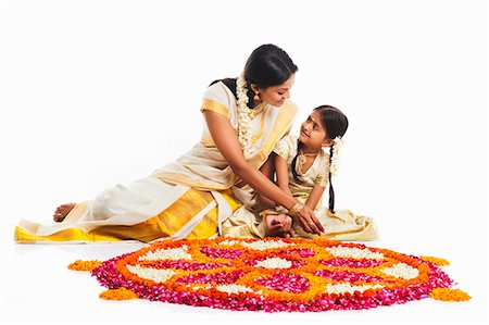 South Indian woman making a rangoli of flowers with her daughter at Onam Stock Photo - Premium Royalty-Free, Code: 630-07071858