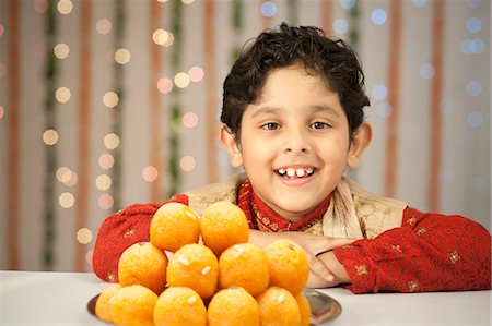 simsearch:700-00195618,k - Boy smiling and a stack of laddoo on Diwali Stock Photo - Premium Royalty-Free, Code: 630-07071955