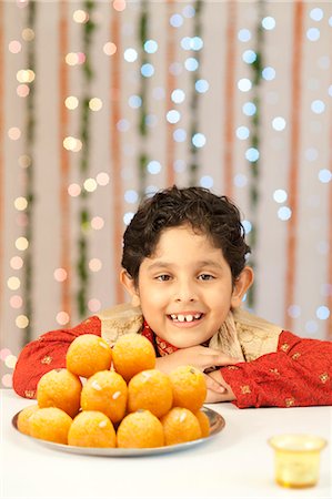 simsearch:700-00195618,k - Boy smiling and a plate of laddoo on Diwali Stock Photo - Premium Royalty-Free, Code: 630-07071956