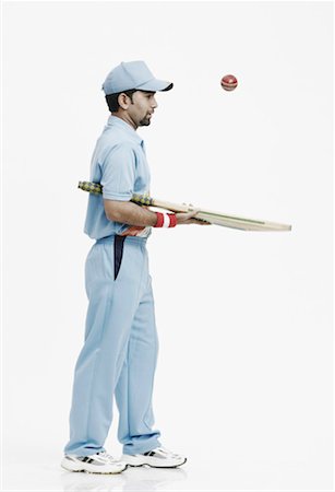 Side profile of a young man playing with a cricket bat and a cricket ball Stock Photo - Premium Royalty-Free, Code: 630-01077124