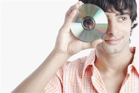 Young man holding a compact disk in front of his face Stock Photo - Premium Royalty-Free, Code: 630-01078010