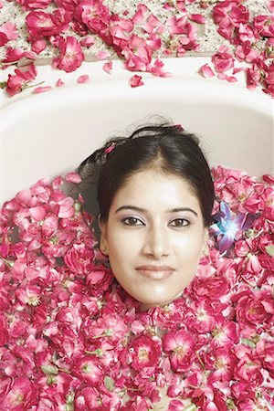 High angle view of a young woman lying in a bathtub covered with flower petals Stock Photo - Premium Royalty-Free, Code: 630-01078212