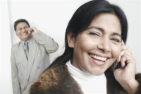simsearch:630-01076466,k - Portrait of a businesswoman talking on a mobile phone with a businessman standing behind her Stock Photo - Premium Royalty-Free, Code: 630-01079384