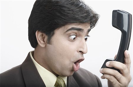 simsearch:640-01350815,k - Close-up of a businessman making a face in front of a telephone receiver Stock Photo - Premium Royalty-Free, Code: 630-01079436