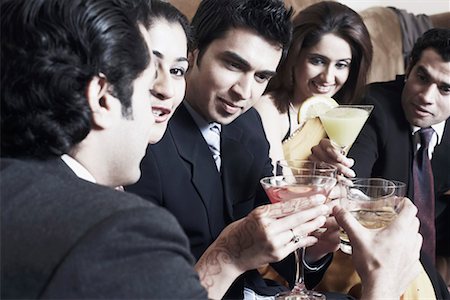 Close-up of three young men and two young women raising a toast with martini and whiskey glasses Stock Photo - Premium Royalty-Free, Code: 630-01079993