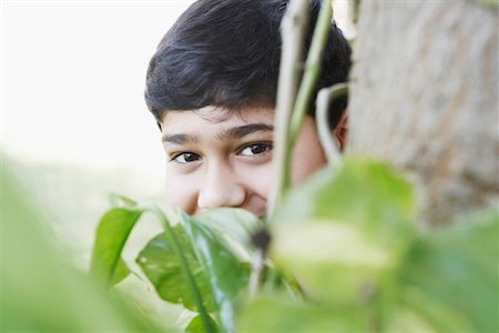Portrait of a boy peeping from behind a tree Foto de stock - Sin royalties Premium, Código: 630-01127300