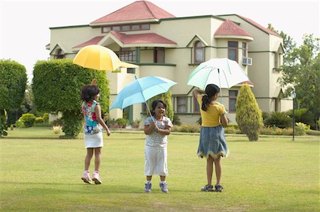 Rear view of three girls holding umbrellas and standing in a lawn Stock Photo - Premium Royalty-Free, Code: 630-01192045