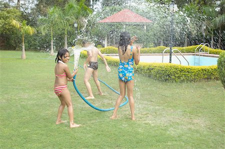 Girl spraying water on her friends with a hose Stock Photo - Premium Royalty-Free, Code: 630-01192058