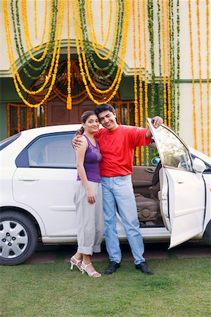 Portrait of a young couple standing near the open door of a car and smiling Stock Photo - Premium Royalty-Free, Code: 630-01192375