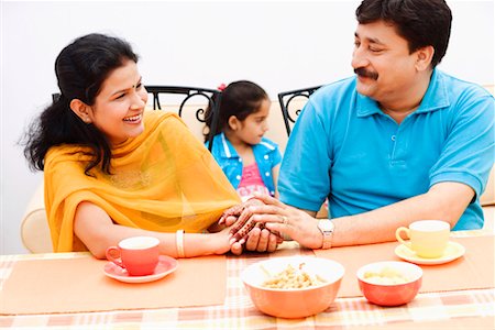 simsearch:630-01296751,k - Couple sitting at the dining table and holding hands with their daughter sitting behind them Stock Photo - Premium Royalty-Free, Code: 630-01296731