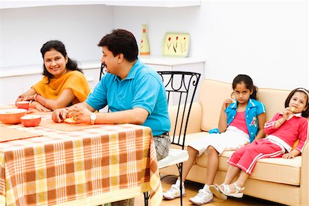 simsearch:630-01296751,k - Couple sitting at the dining table with their two daughters sitting behind them Stock Photo - Premium Royalty-Free, Code: 630-01297157