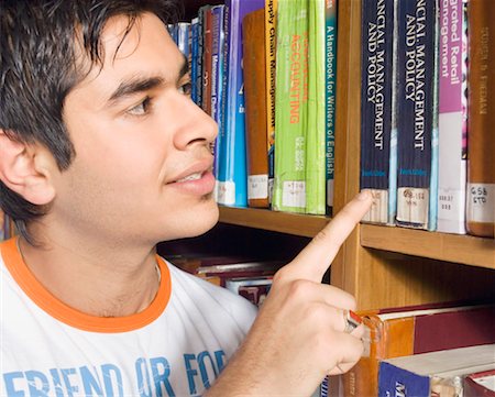 Close-up of a male college student selecting a book from a library shelf Stock Photo - Premium Royalty-Free, Code: 630-01490425