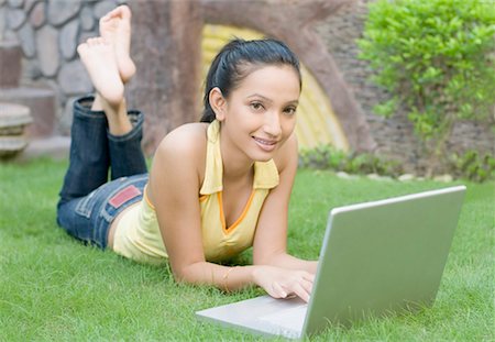 Portrait of a young woman lying on the grass and using a laptop Stock Photo - Premium Royalty-Free, Code: 630-01490479