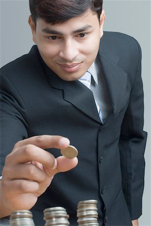 rupee - Close-up of a businessman holding an Indian coin over the stacks of coin Stock Photo - Premium Royalty-Free, Code: 630-01490495