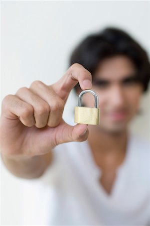 Young man holding a padlock Stock Photo - Premium Royalty-Free, Code: 630-01490830