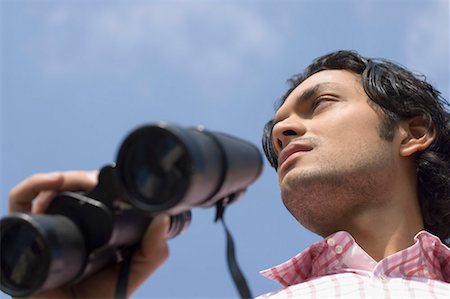 Low angle view of a young man holding a pair of binoculars Stock Photo - Premium Royalty-Free, Code: 630-01490929