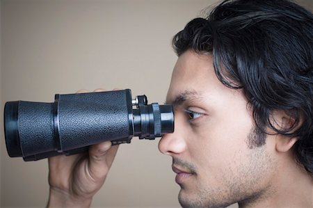 Close-up of a young man looking through a pair of binoculars Stock Photo - Premium Royalty-Free, Code: 630-01490931