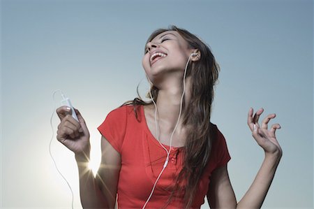 Jeune femme à l'écoute d'un lecteur MP3 et rire Photographie de stock - Premium Libres de Droits, Code: 630-01491372