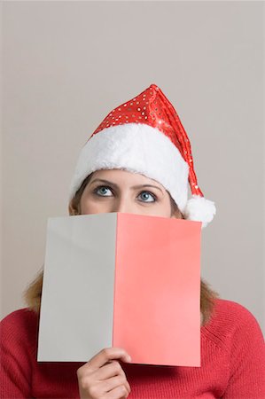 santa claus hat - Close-up of a young woman holding a greeting card in front of her face Stock Photo - Premium Royalty-Free, Code: 630-01491607