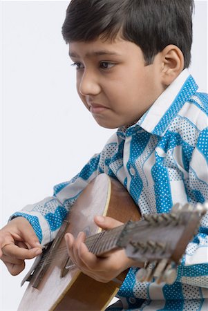 Side profile of a boy playing the mandolin Stock Photo - Premium Royalty-Free, Code: 630-01491725