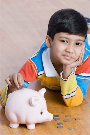 piggy - Portrait of a boy putting a coin in a piggy bank Stock Photo - Premium Royalty-Free, Code: 630-01491733