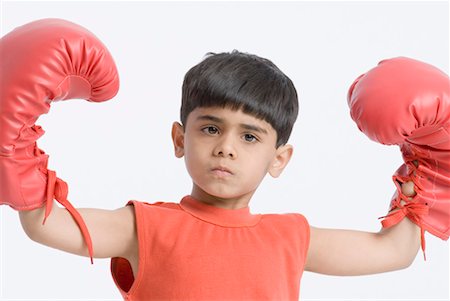 Portrait of a boy wearing boxing gloves and flexing his muscles Stock Photo - Premium Royalty-Free, Code: 630-01491817