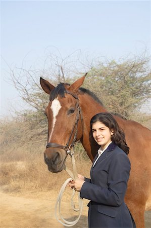 Portrait d'une jeune adolescente debout avec un cheval et souriant Photographie de stock - Premium Libres de Droits, Code: 630-01491834