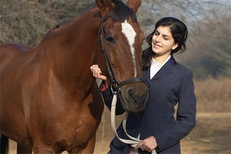 Close-up of a teenage girl standing with a horse and smiling Stock Photo - Premium Royalty-Free, Code: 630-01491883