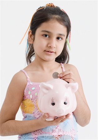 piggy - Portrait of a girl dropping a coin into a piggy bank Stock Photo - Premium Royalty-Free, Code: 630-01492100