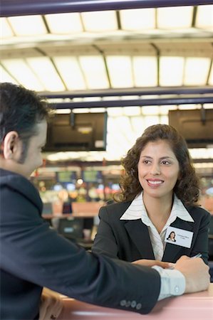 Young man giving a passport to an airline check-in attendant at a counter Stock Photo - Premium Royalty-Free, Code: 630-01492859