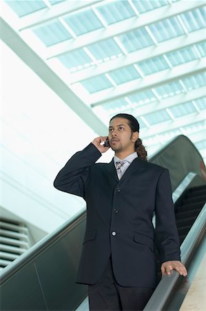 simsearch:630-01873072,k - Low angle view of a businessman standing on an escalator and talking on a mobile phone Stock Photo - Premium Royalty-Free, Code: 630-01492863